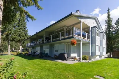 a large house with a balcony and a lawn at 1BR and Sofabed at Whistler on the Lake, Lakefront, Serene Setting, Wood Burning Fireplace in Whistler