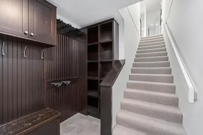 a staircase in a house with white walls and brown cabinets at 3BR in Gleneagle, Soaker Tub with Skylight, Wood Burning Fireplace, Spacious Layout in Whistler