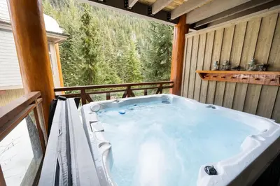 a jacuzzi tub in a cabin with a large window at 3BR Luxury Home in Taluswood, Hot Tub, Ski In, Ski Out, Two-Car Garage, Village Parking in Whistler