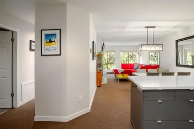 a white kitchen and living room with a red couch at 2BR in Powderhorn, Near Blackcomb, Double-Sided Fireplace, Rooftop Hot Tub, Parking in Whistler