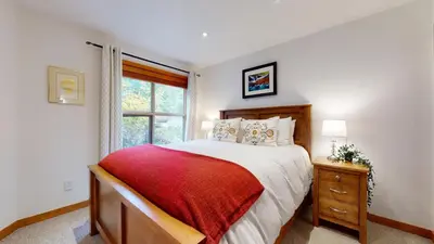 a bedroom with a large bed and a window at 2BR in Blackcomb Greens, Wood Burning Fireplace, Communal Hot Tub, Nature Views in Whistler