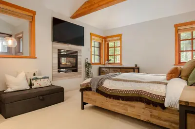 a bedroom with a bed and a fireplace and a tv at Luxury Mountain Retreat with PRIVATE Hot Tub by Harmony Whistler in Whistler