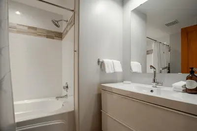 a white bathroom with a sink and a tub and a mirror at Luxury Mountain Retreat with PRIVATE Hot Tub by Harmony Whistler in Whistler