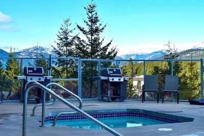 a swimming pool with a grill and mountains in the background at 2BR in Ironwood, Fireplace, Common Area Hot Tub, Private Patio, Parking in Whistler
