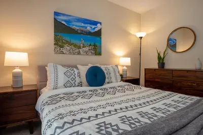 a bedroom with a bed and two lamps and a mirror at 2BR plus Loft in Wildwood Lodge, Free Ski Bus, Hot Tub and Pool, Private Patio, Parking in Whistler
