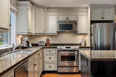 a kitchen with white cabinets and stainless steel appliances at 4BR in Blueberry Hill Estates, Lake View, Tranquil Setting, Gourmet Kitchen, Family Sized in Whistler