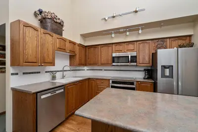 a kitchen with wooden cabinets and a stainless steel refrigerator at 2BR in The Lynx, Family Sized, Mountain Views, Private Balcony, Tranquil Location, Parking in Whistler