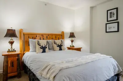 a bedroom with a large bed with two lamps at 2BR plus Den in Woodrun, True Ski In, Ski Out, Heated Floors, Pool and Hot Tub, King Ensuite in Whistler