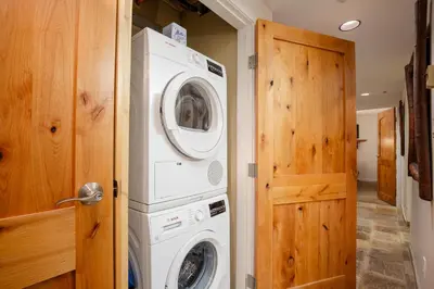 a laundry room with a washer and dryer next to a door at 2BR plus Den in Woodrun, True Ski In, Ski Out, Heated Floors, Pool and Hot Tub, King Ensuite in Whistler