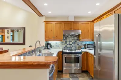a kitchen with wooden cabinets and a stainless steel refrigerator at 3BR in The Woods, Private Hot Tub, Wood Burning Fireplace, King Ensuite, Private Garage in Whistler