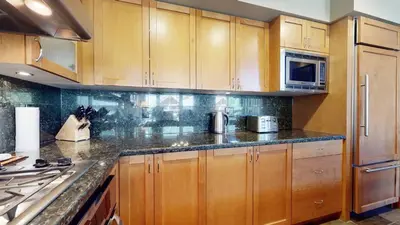 a kitchen with wooden cabinets and a counter top at 3BR in Montbello, Cozy Townhouse, Private Hot Tub, Near Village, Fireplace in Whistler