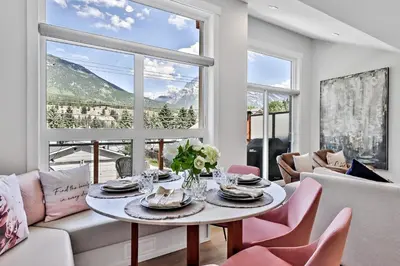 a living room with a table and pink chairs at The Alpine Escape by Samsara Resort Top View Downtown 4BR & 3BTH in Canmore