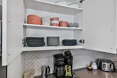 a kitchen with white cabinets and plates and a coffee maker at The Alpine Escape by Samsara Resort Top View Downtown 4BR & 3BTH in Canmore
