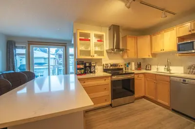 a kitchen with wooden cabinets and a counter top at Top Floor Condo - 2BR & AC with Mountain Views in Canmore