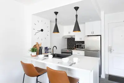 a kitchen with a white counter and a clock on the wall at Contemporary & Spacious Slopeside 1BR Getaway in Whistler