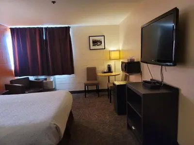 a hotel room with a bed and a flat screen tv at Roadking Inns Motel in Calgary