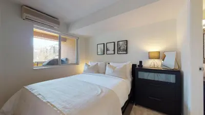 a bedroom with a white bed and a window at 1BR and Den in Marketplace Lodge, Gas Fireplace, Village Location, Complex Hot Tub in Whistler