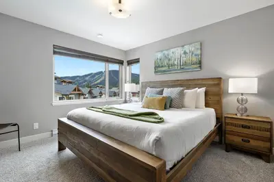 a bedroom with a large bed and a window at Spacious Modern Ski-in Ski-out with Hot Tub Townhouse in Sun Peaks