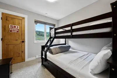 a bedroom with two bunk beds and a window at Spacious Modern Ski-in Ski-out with Hot Tub Townhouse in Sun Peaks
