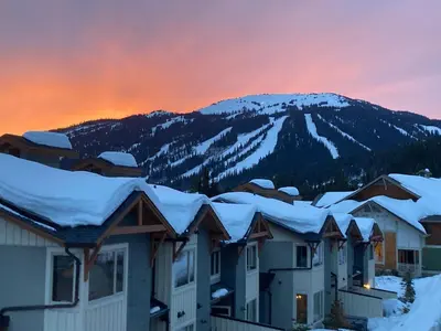 a row of houses covered in snow at sunset at Spacious Modern Ski-in Ski-out with Hot Tub Townhouse in Sun Peaks