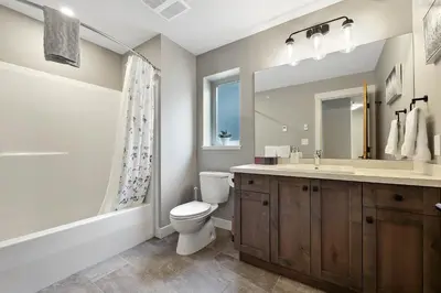 a bathroom with a toilet and a sink and a mirror at Spacious Modern Ski-in Ski-out with Hot Tub Townhouse in Sun Peaks