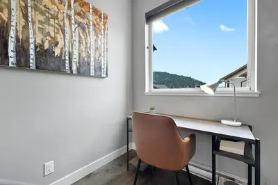 a desk with a chair in a room with a window at Spacious Modern Ski-in Ski-out with Hot Tub Townhouse in Sun Peaks