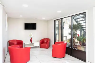 a waiting room with red chairs and a tv at Econo Lodge in Prince George