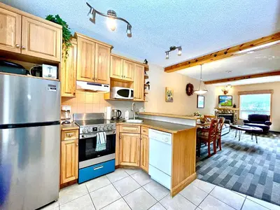 a kitchen with wooden cabinets and a dining room at MountainView -PrivateChalet Sleep7- 5min to DT Vacation Home in Canmore