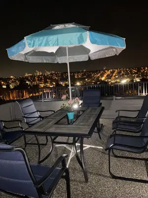 a table and chairs with an umbrella on a roof at Six minutes to Rupert station in Vancouver