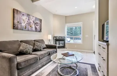a living room with a couch and a glass table at BANFF WOODS LODGE in Canmore