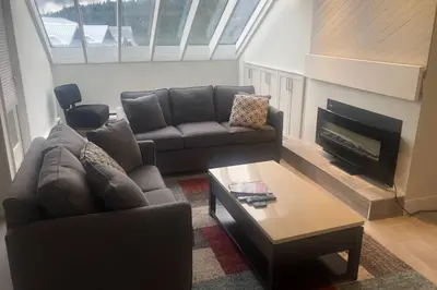 a living room with a couch and a fireplace at Hearthstone Lodge loft, Village centre, Private Hot tub, sleeps 6 in Whistler