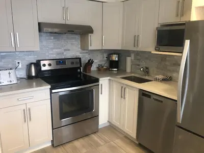 a kitchen with white cabinets and stainless steel appliances at Hearthstone Lodge loft, Village centre, Private Hot tub, sleeps 6 in Whistler