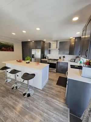 a kitchen with a white counter and two bar stools at JoyVeal’s Homey Place in Sechelt