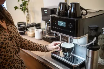 a woman is putting a cup in a coffee machine at The Copeland in Revelstoke