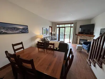 a dining room and living room with a table and a couch at Trappers Landing #34 by Bear Country in Sun Peaks
