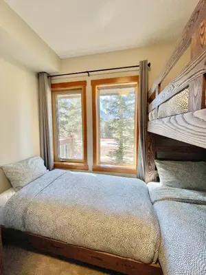 a bedroom with a bunk bed and two windows at Newly Renovated Grizzly Lodge, Spacious 3BR 2BA with open pool, hot tub in Canmore