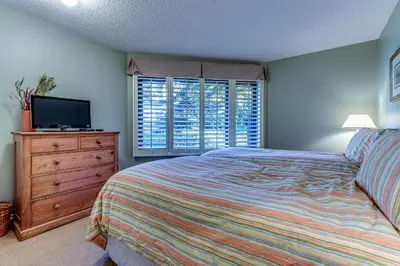 a bedroom with a bed and a dresser and a television at Wintergreen 27 - Townhome in Whistler