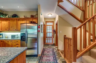 a kitchen with a stainless steel refrigerator and wooden cabinets at Mountain Star 28 Hot Tub in Whistler