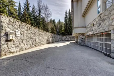 a stone wall next to a building with a garage at Greystone Lodge 413 - Largest in Whistler