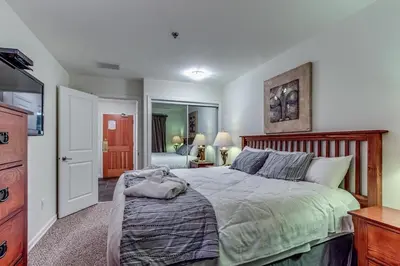a bedroom with a large bed with a wooden headboard at Greystone Lodge 413 - Largest in Whistler