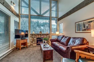 a living room with a leather couch and a fireplace at Greystone Lodge 401 Ski-in Out in Whistler