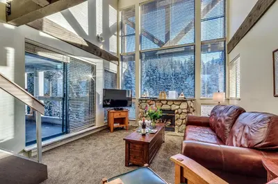 a living room with a leather couch and a fireplace at Greystone Lodge 401 Ski-in Out in Whistler