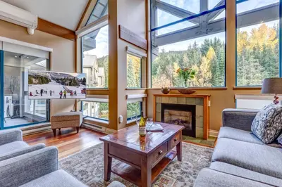 a living room with large windows and a fireplace at Greystone Lodge 408 Luxury in Whistler
