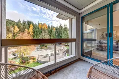 a balcony with two chairs and a large window at Greystone Lodge 408 Luxury in Whistler