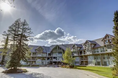 a large apartment building with a tree in the foreground at Greystone Lodge 221 Ski-in Out in Whistler