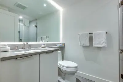 a white bathroom with a toilet and a sink at Greystone Lodge 310 Ski-in Out in Whistler