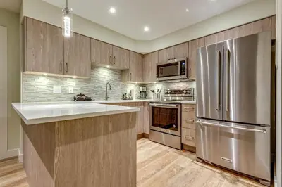 a kitchen with a stainless steel refrigerator and wooden cabinets at Greystone Lodge 109 Ski-in Out in Whistler