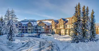 a large building covered in snow with trees in front at Greystone Lodge 328 Ski-in Out in Whistler
