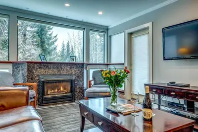 a living room with a fireplace and a vase of flowers on a table at Greystone Lodge 207 Ski-in Out in Whistler