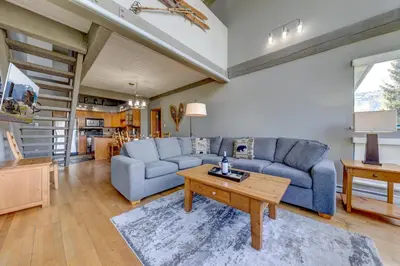 a living room with a blue couch and a table at Greystone Lodge 311 Ski-in Out in Whistler